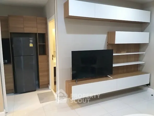 Modern living room with sleek TV unit and integrated kitchen appliances.