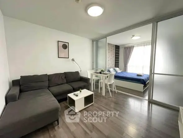 Modern living room with sleek furniture and cozy bedroom in open layout apartment.