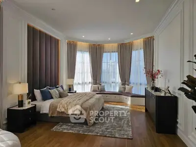 Luxurious bedroom with elegant decor, large windows, and cozy seating area, perfect for relaxation and comfort.