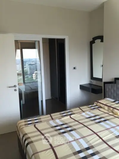 Modern bedroom with stylish decor and city view, featuring a sleek sliding door and elegant mirror.