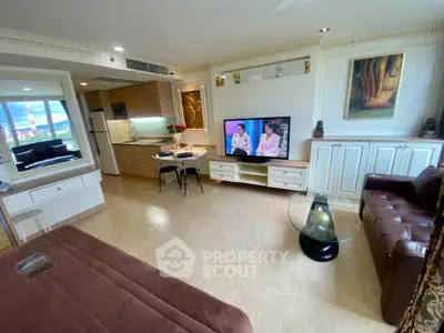 Luxurious living room with modern decor and open kitchen layout, featuring a cozy seating area and large TV.