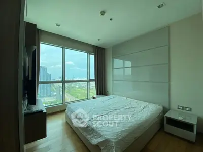 Spacious bedroom with large window offering stunning city views in modern apartment.