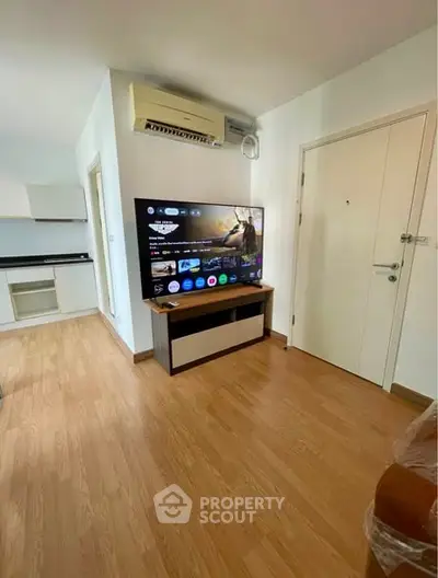 Modern living room with wooden flooring, flat-screen TV, and air conditioning unit.