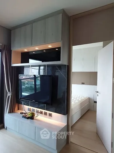 Modern living room with wall-mounted TV and view into a stylish bedroom