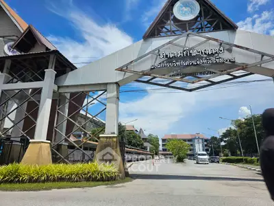 Impressive entrance of a modern building with clear blue skies and lush greenery.