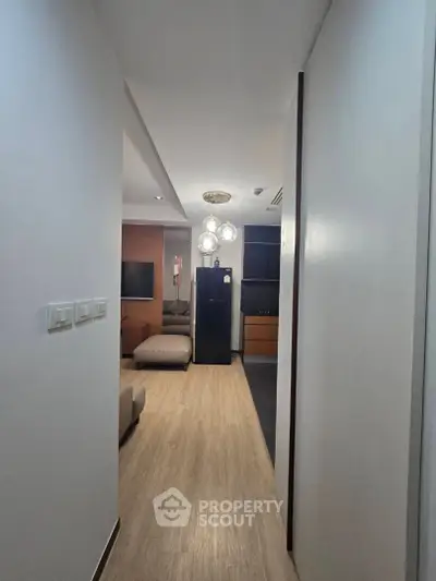 Modern apartment hallway leading to a cozy living room with stylish lighting.