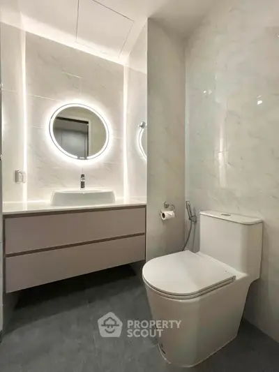 Modern bathroom with sleek fixtures and illuminated mirror, showcasing contemporary design and elegance.
