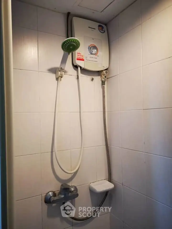 Compact bathroom shower area with water heater and tiled walls