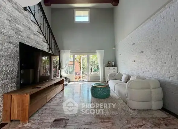 Spacious living room with high ceilings and large windows offering natural light and garden view.