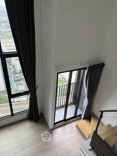 Modern loft apartment with high ceilings and city view from balcony.
