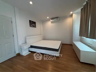 Spacious modern bedroom with wooden flooring and minimalist design