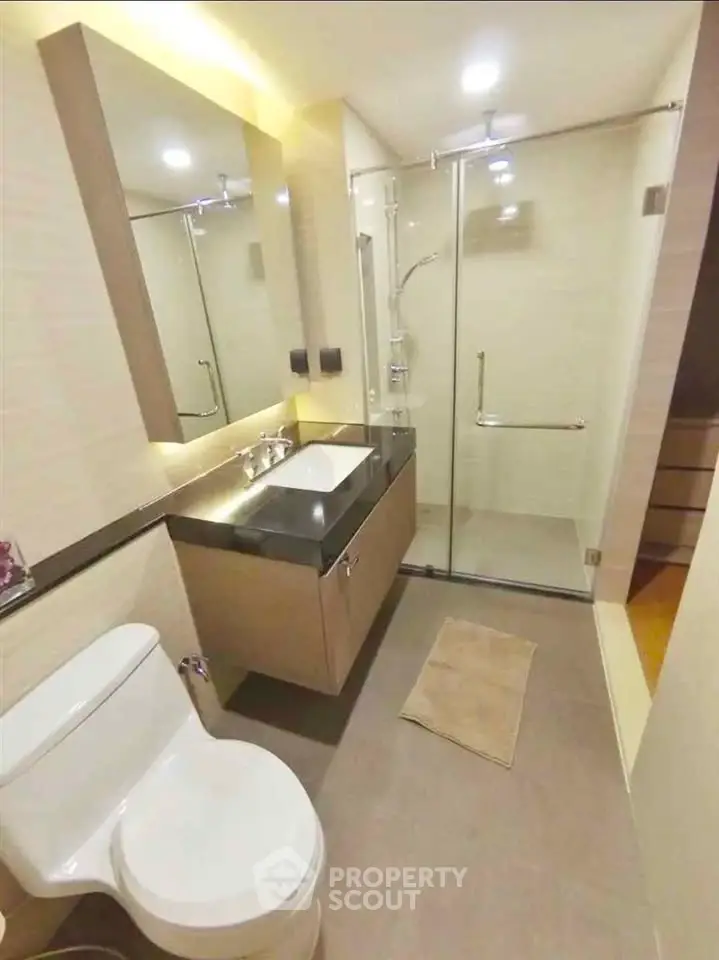 Modern bathroom with glass shower and sleek vanity in a contemporary apartment.