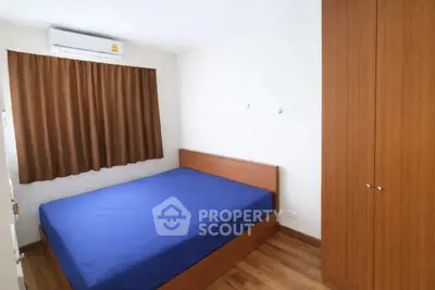 Cozy bedroom with wooden flooring and blue bedding in modern apartment