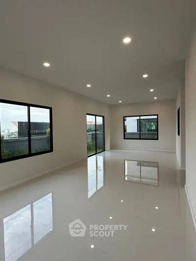 Spacious modern living room with large windows and glossy tiled floors