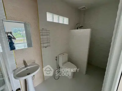 Modern bathroom with sleek design and natural light, featuring a shower and toilet.