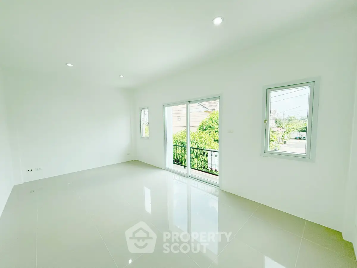Spacious and bright living room with large windows and glossy tiled floor, offering a serene garden view.