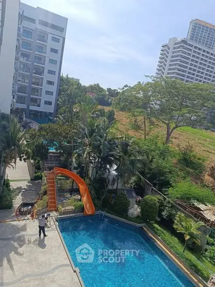 Stunning pool area with slide and lush greenery in modern residential complex.