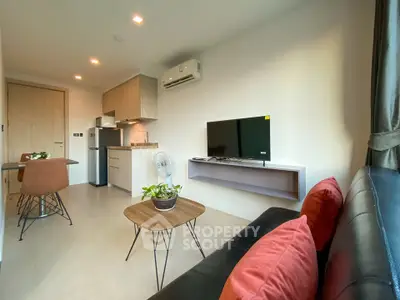 Modern living room with sleek furniture and compact kitchen in open layout apartment.