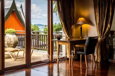 Luxurious room with elegant decor and stunning balcony view in tropical setting.