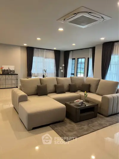 Spacious modern living room with elegant sectional sofa and large windows.