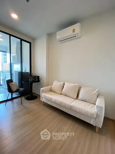 Modern living room with sleek design and air conditioning, featuring a cozy white sofa and stylish decor.