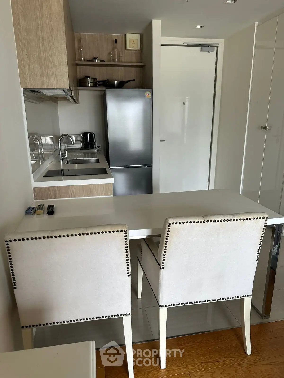 Modern compact kitchen with dining area, featuring sleek cabinetry and stainless steel appliances.