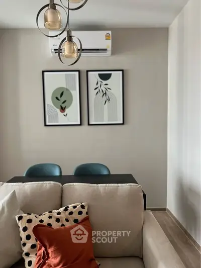 Modern living room with stylish decor and air conditioning, featuring a cozy sofa and contemporary artwork.