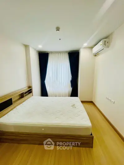Spacious bedroom with wooden flooring and natural light, featuring a modern air conditioning unit.