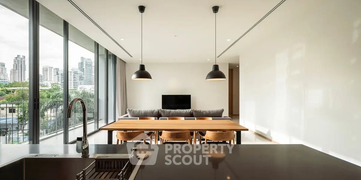 Modern open-plan living room with city view, featuring sleek furniture and large windows.