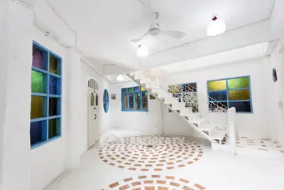 Charming interior with unique staircase and colorful windows in a bright, airy space.