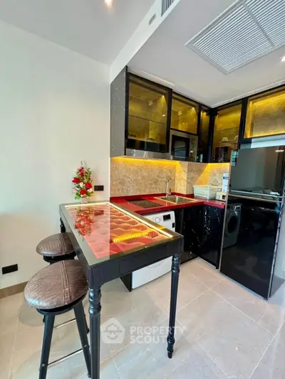 Modern kitchen with sleek black cabinets and built-in appliances, featuring a stylish breakfast bar.