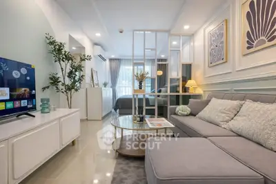 Modern living room with stylish decor and open layout leading to bedroom, featuring a cozy sofa and flat-screen TV.