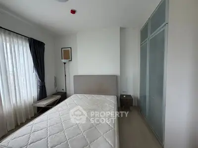 Modern bedroom with large window and minimalist decor, featuring a comfortable bed and ample natural light.