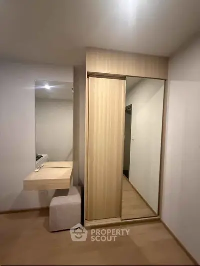Modern bedroom with sleek mirrored wardrobe and minimalist dressing table.