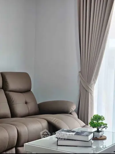 Cozy living room with plush leather sofa and elegant curtains, perfect for relaxation.