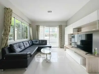 Spacious living room with modern black leather sofa and large TV unit
