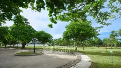 Spacious garden with lush greenery and paved pathway in serene residential area.
