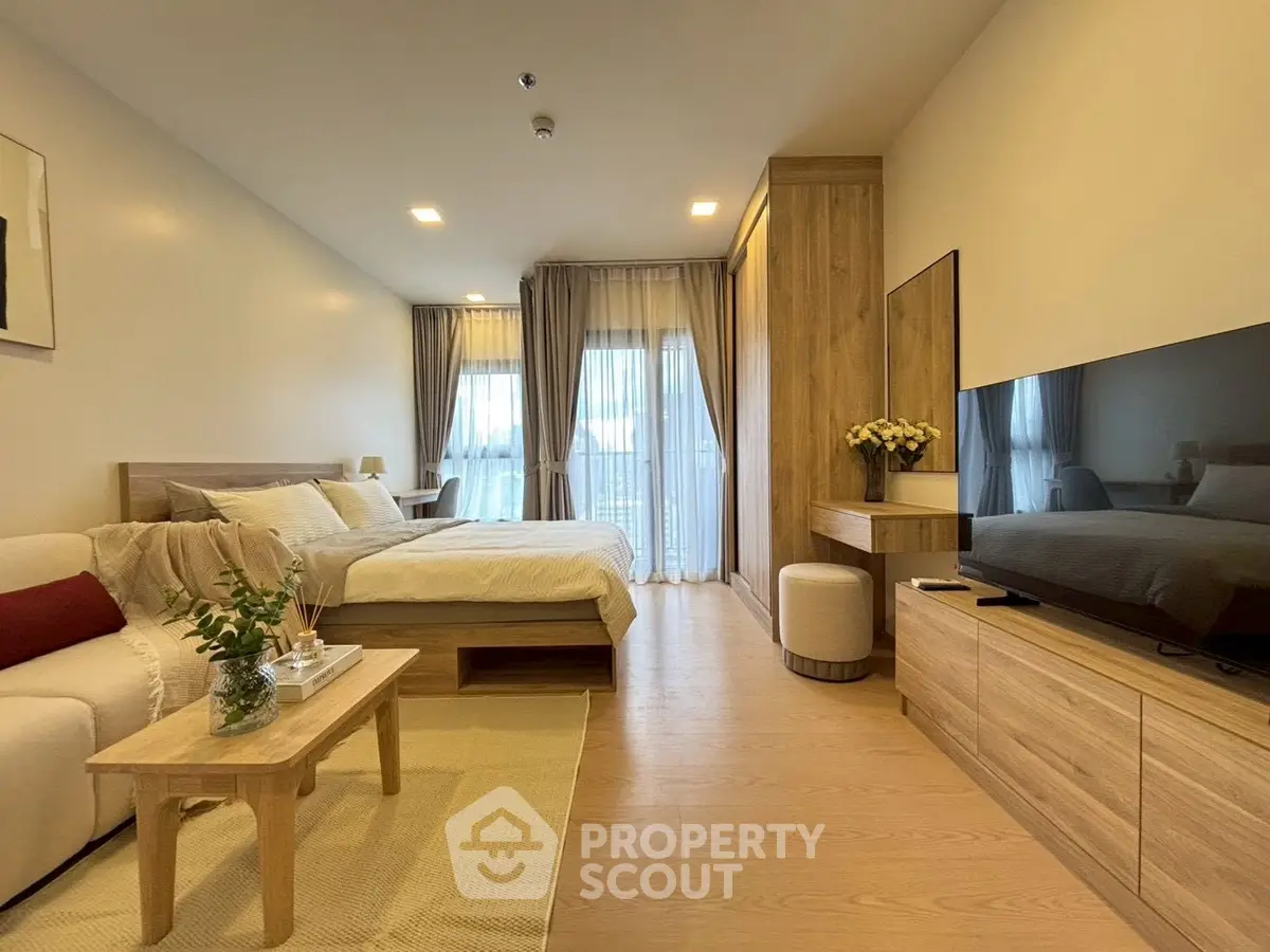 Spacious modern bedroom with elegant decor and natural light, featuring a cozy seating area and stylish wooden furniture.