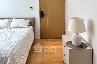 Cozy bedroom with modern decor and wooden flooring, featuring a stylish lamp and comfortable bed.