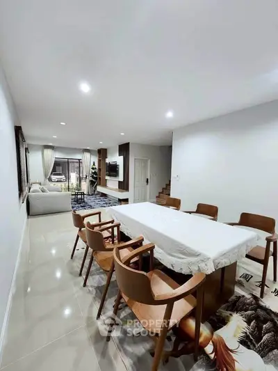 Spacious modern living and dining area with elegant wooden furniture and bright lighting.
