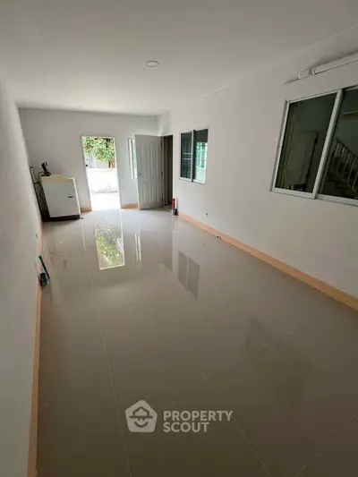 Spacious unfurnished room with glossy tiled floor and large windows, perfect for customization.