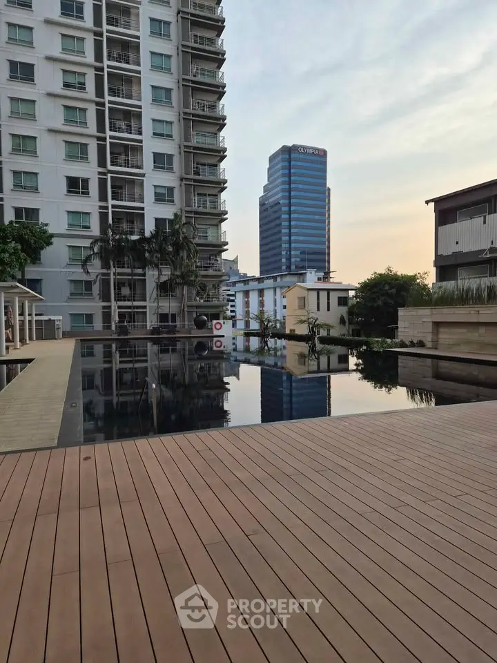Luxurious apartment building with serene poolside view and cityscape backdrop.