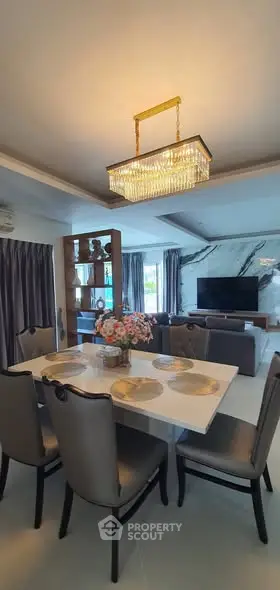 Luxurious dining and living area with elegant chandelier and modern decor