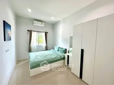 Modern bedroom with minimalist design, featuring a sleek wardrobe and a cozy bed under natural light.
