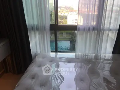 Luxurious bedroom with pool view and floor-to-ceiling windows in modern apartment.