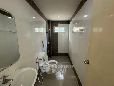 Modern bathroom with sleek design and natural light from small windows.