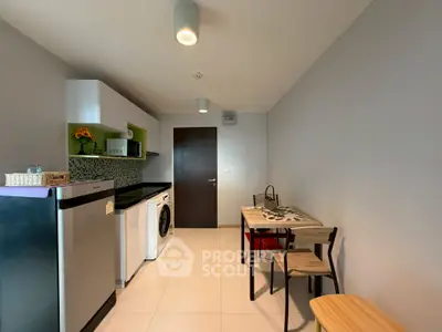 Modern kitchen with sleek appliances and dining area in compact layout.