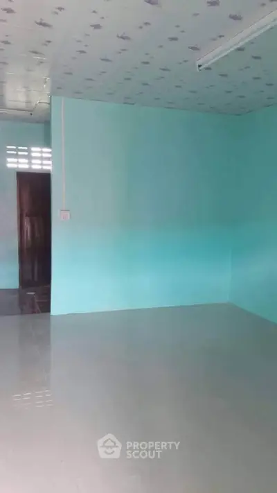 Spacious empty room with teal walls and tiled floor, ready for customization.