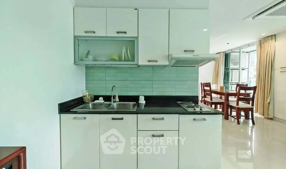 Modern kitchen with sleek white cabinets and dining area in open layout apartment.