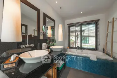 Luxurious bathroom with dual sinks and a spacious bathtub, featuring modern fixtures and large window view.